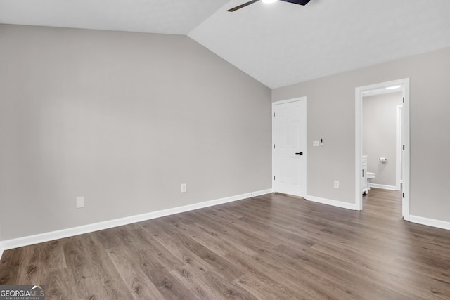 unfurnished bedroom featuring lofted ceiling, wood finished floors, a ceiling fan, connected bathroom, and baseboards