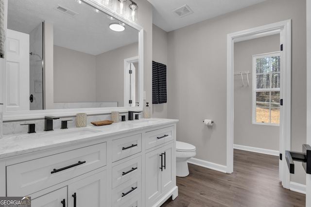 full bath featuring double vanity, visible vents, toilet, and a sink