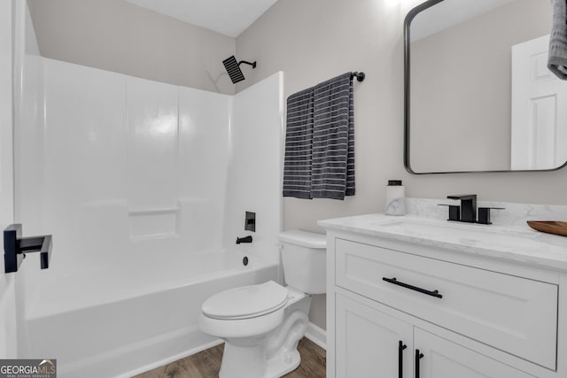 full bath with tub / shower combination, wood finished floors, toilet, and vanity