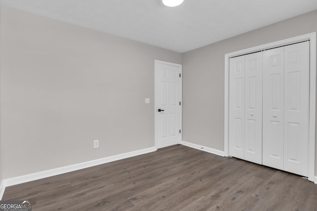 unfurnished bedroom with baseboards, wood finished floors, and a closet