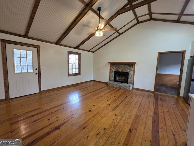 unfurnished living room featuring high vaulted ceiling, a ceiling fan, a stone fireplace, hardwood / wood-style floors, and beamed ceiling