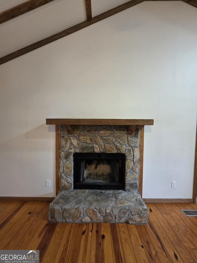 room details with visible vents, wood finished floors, baseboards, and a stone fireplace