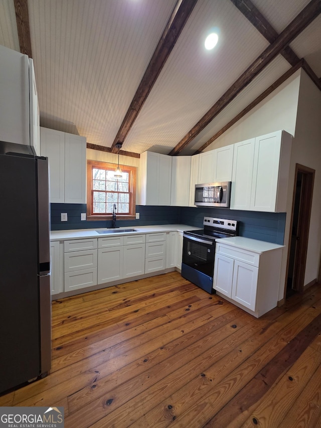 kitchen featuring tasteful backsplash, vaulted ceiling with beams, stainless steel appliances, and a sink