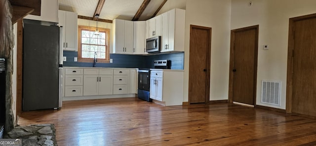 kitchen with tasteful backsplash, hardwood / wood-style flooring, appliances with stainless steel finishes, beam ceiling, and visible vents