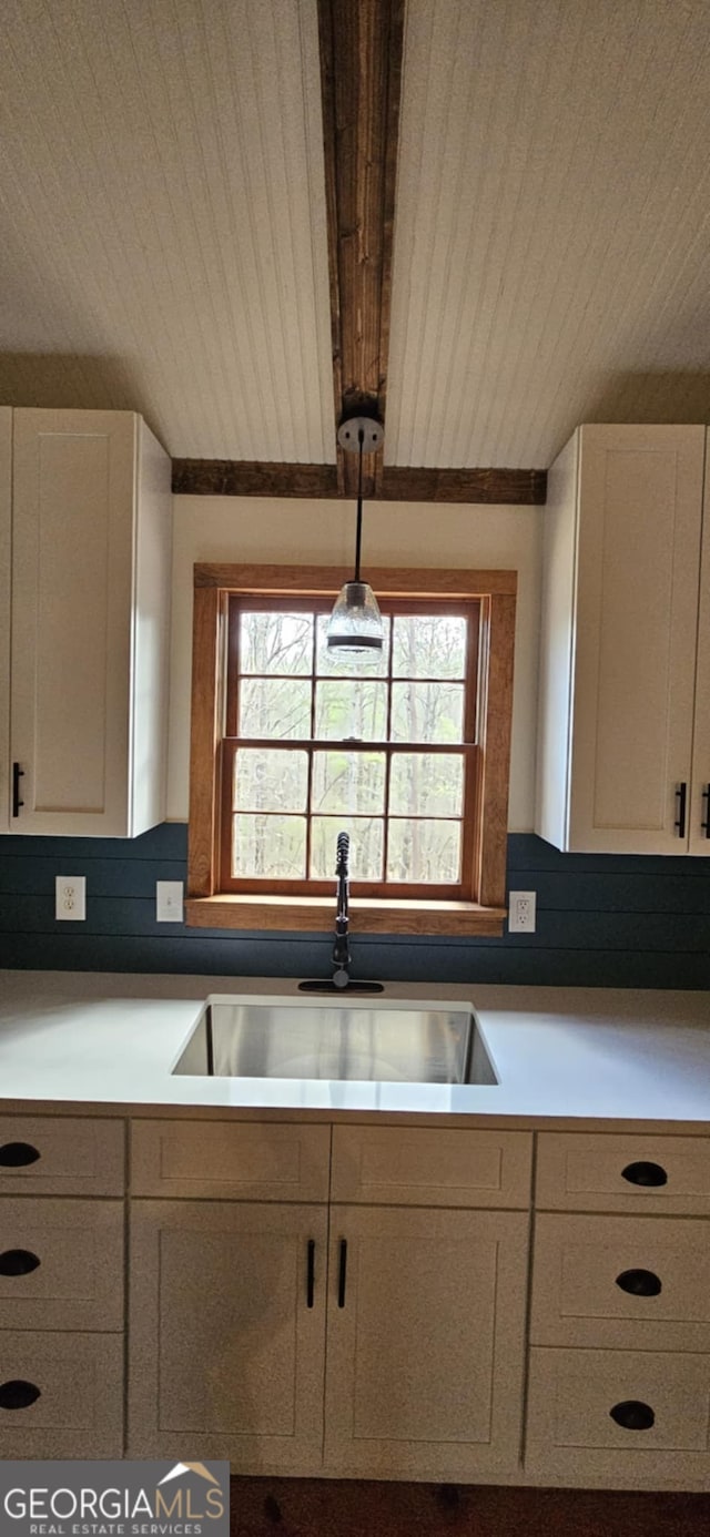 kitchen featuring white cabinets, a healthy amount of sunlight, wooden ceiling, and a sink