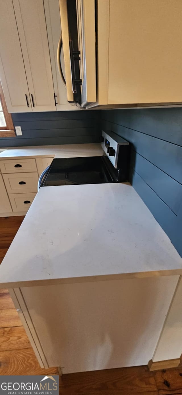 room details featuring dark wood finished floors, range with electric cooktop, white cabinets, and light countertops