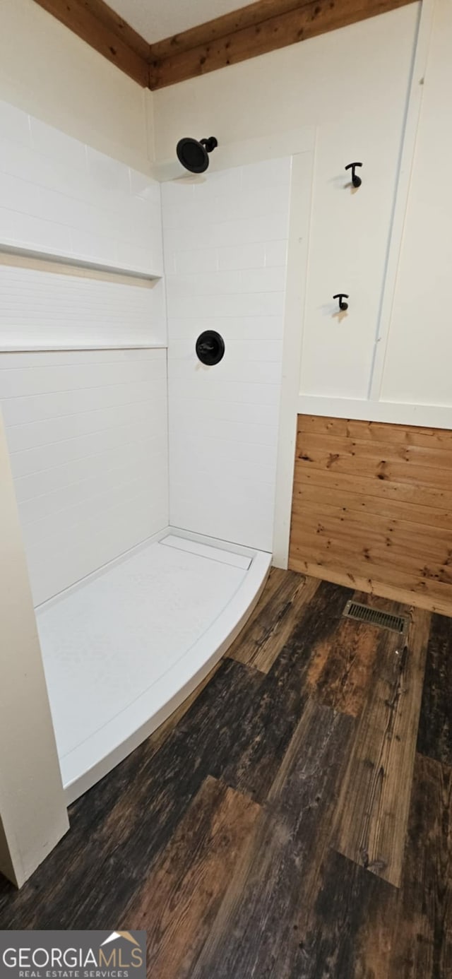 full bathroom featuring a tile shower, hardwood / wood-style floors, and visible vents