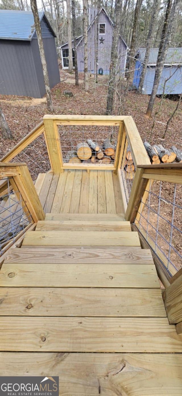 wooden terrace featuring a storage shed and an outdoor structure