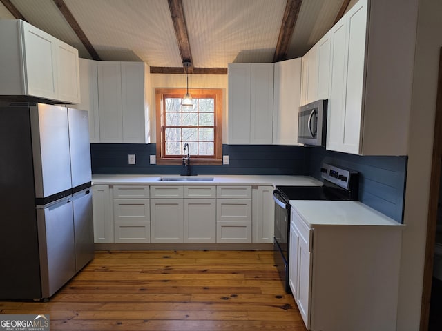 kitchen featuring light wood-type flooring, light countertops, a sink, and appliances with stainless steel finishes