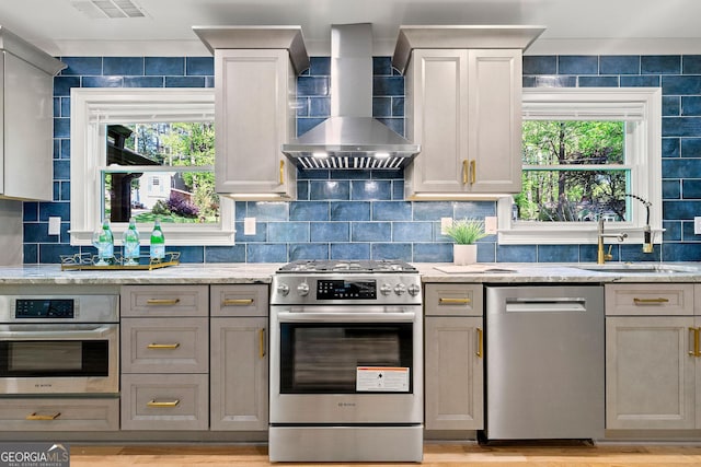 1186 Thomas Rd, Decatur, GA 30030 - kitchen featuring appliances with stainless steel finishes, wall chimney range hood, a sink, and light stone countertops