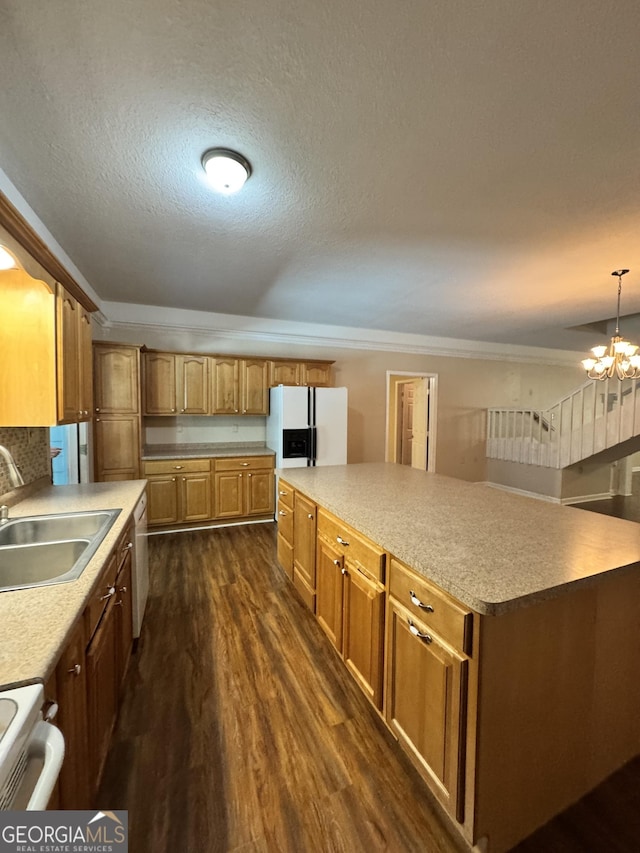 kitchen with an inviting chandelier, a sink, dark wood-type flooring, white appliances, and a kitchen island