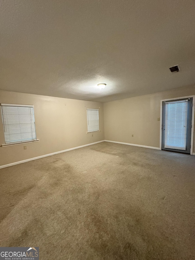unfurnished room with baseboards, carpet flooring, and a textured ceiling