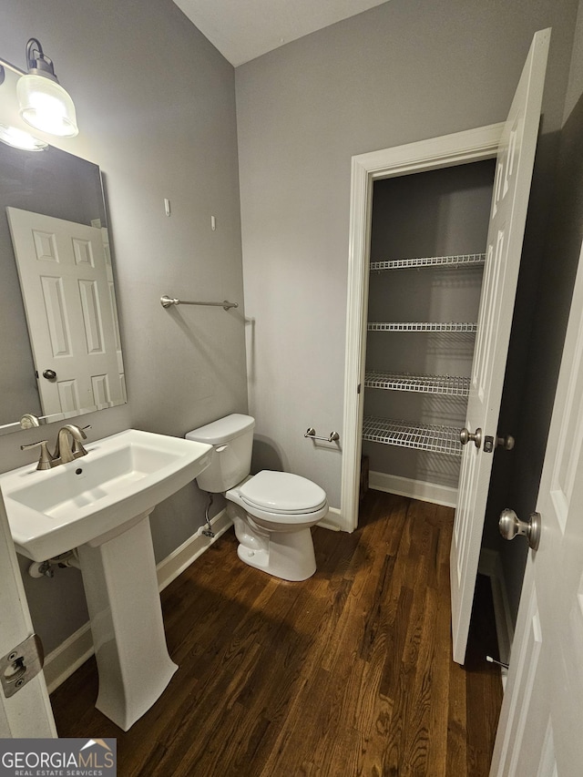 bathroom featuring toilet, wood finished floors, and baseboards