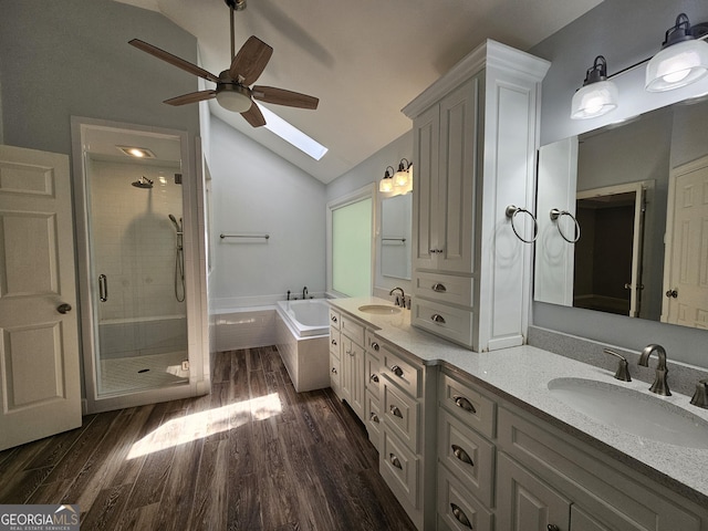 bathroom featuring vaulted ceiling with skylight, a shower stall, a ceiling fan, and a sink