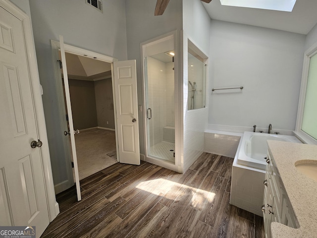 bathroom with a bath, a stall shower, visible vents, wood finished floors, and vanity