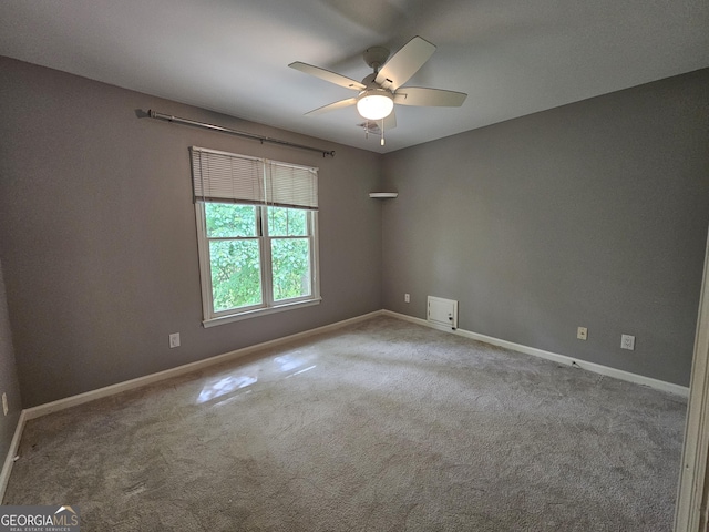 carpeted empty room featuring a ceiling fan and baseboards