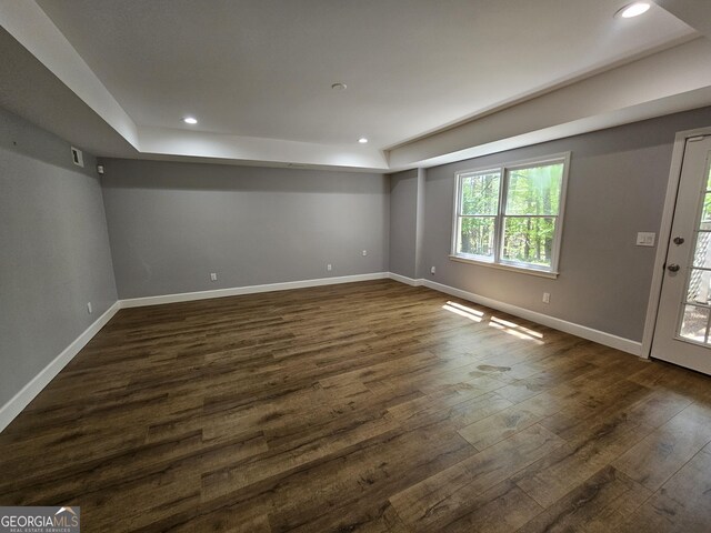 spare room featuring a tray ceiling, baseboards, dark wood-type flooring, and recessed lighting