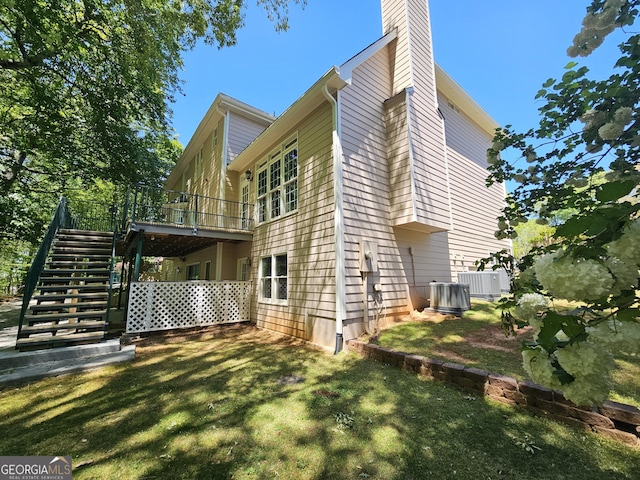back of house with stairway, a chimney, central AC, a lawn, and a deck