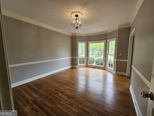unfurnished room featuring a chandelier, wood finished floors, crown molding, and baseboards
