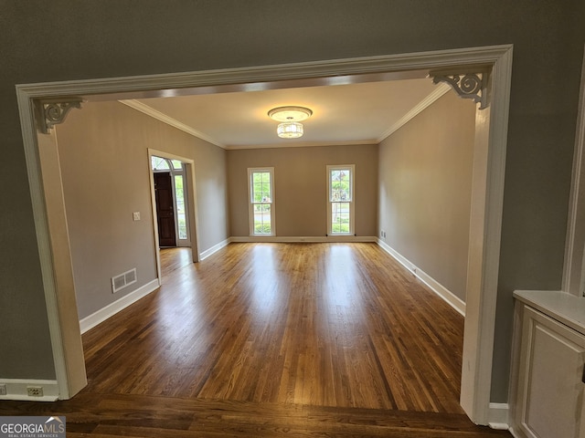 unfurnished dining area featuring wood finished floors, visible vents, crown molding, and baseboards