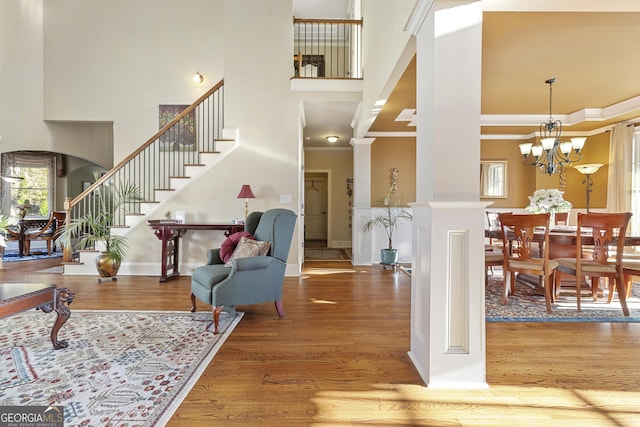 entrance foyer with a high ceiling, wood finished floors, stairs, and decorative columns
