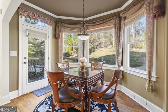 dining area featuring baseboards, crown molding, and wood finished floors