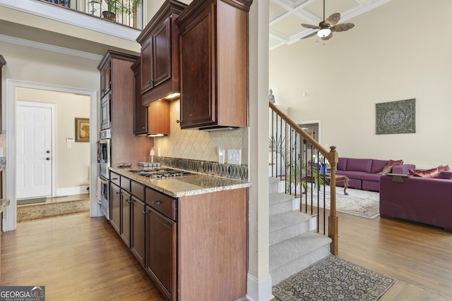 kitchen featuring open floor plan, a high ceiling, backsplash, and stainless steel appliances