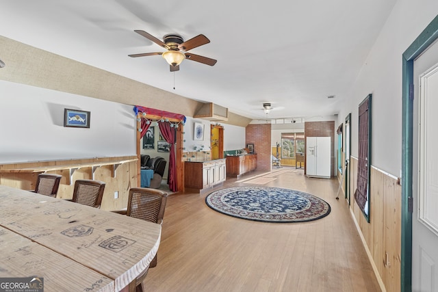 interior space with wooden walls, wood finished floors, and a ceiling fan