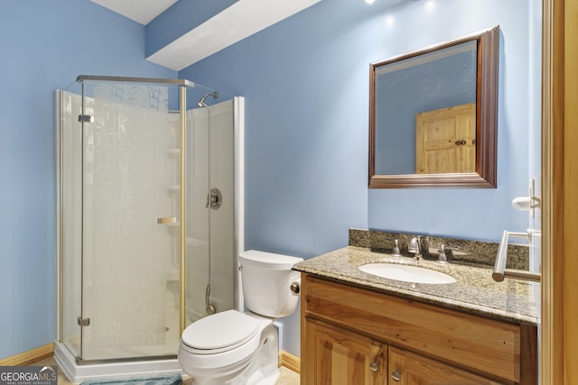 bathroom with a shower stall, toilet, vanity, and baseboards