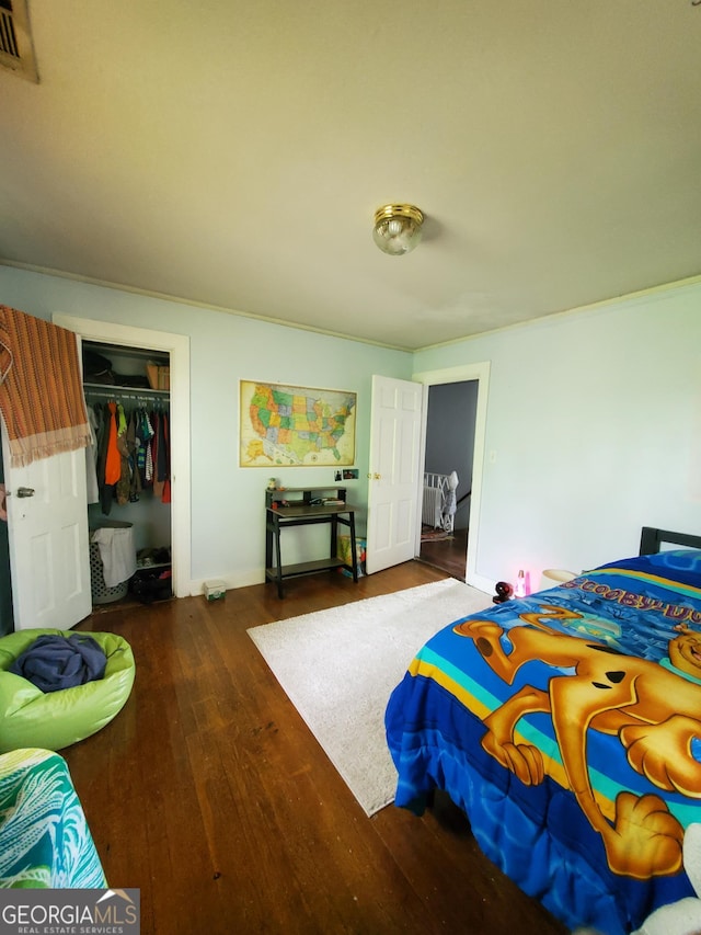 bedroom with baseboards, visible vents, a closet, crown molding, and hardwood / wood-style floors