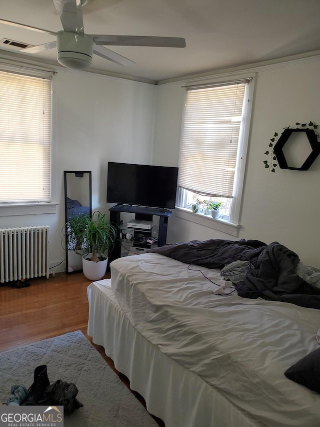 bedroom featuring visible vents, a ceiling fan, wood finished floors, and radiator