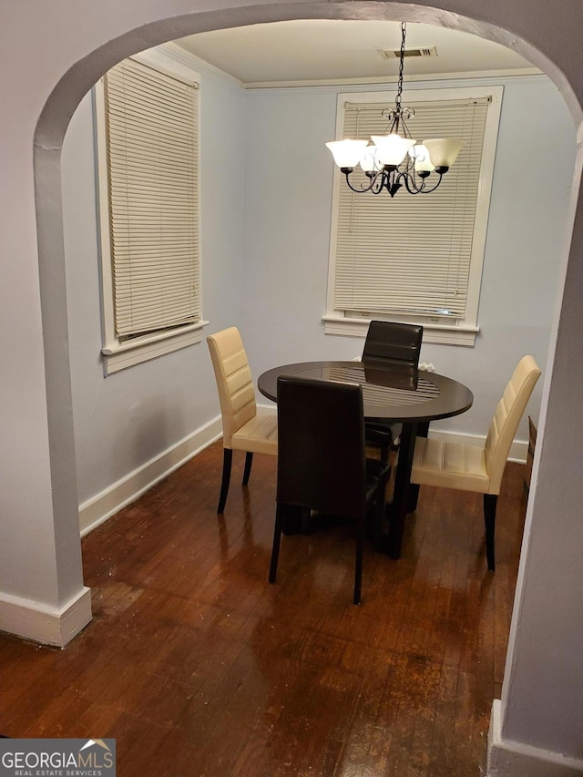 dining room with arched walkways, visible vents, an inviting chandelier, baseboards, and hardwood / wood-style flooring