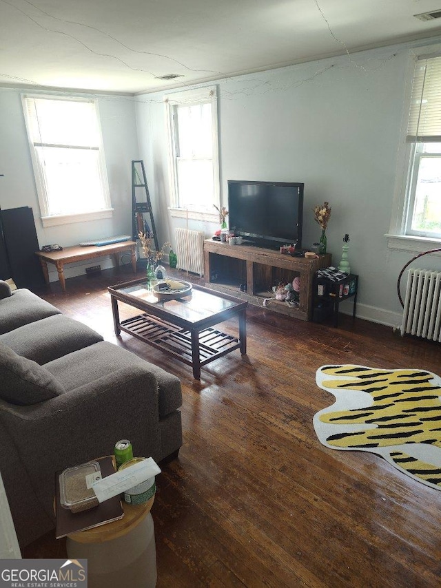 living area with visible vents, wood finished floors, and radiator