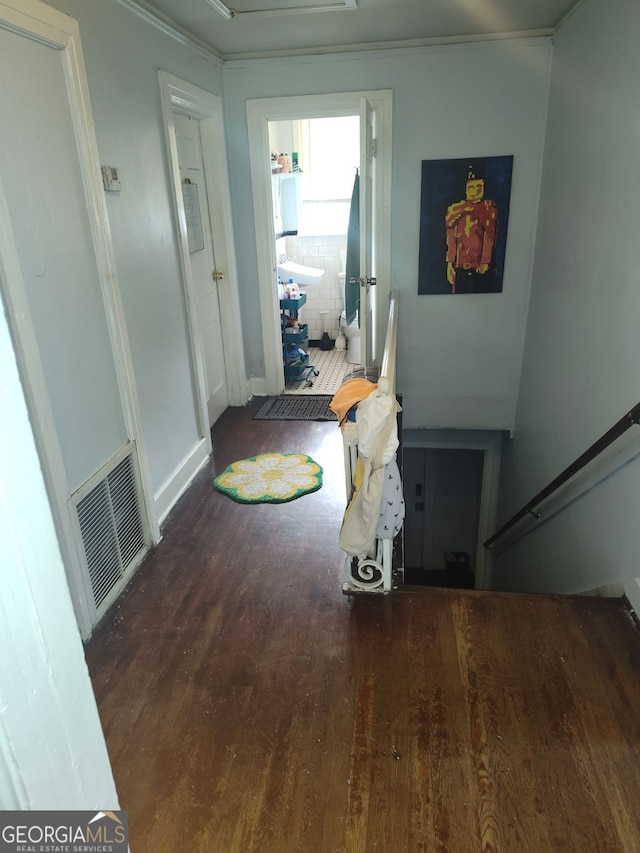 hallway featuring ornamental molding, wood finished floors, and visible vents
