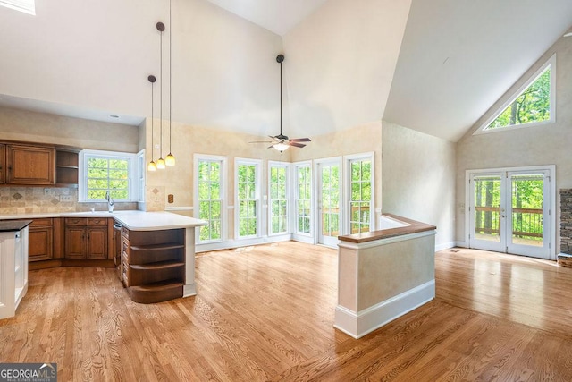 kitchen featuring brown cabinetry, open shelves, light wood-type flooring, high vaulted ceiling, and open floor plan