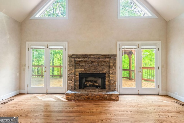 unfurnished living room with high vaulted ceiling, french doors, wood finished floors, and visible vents