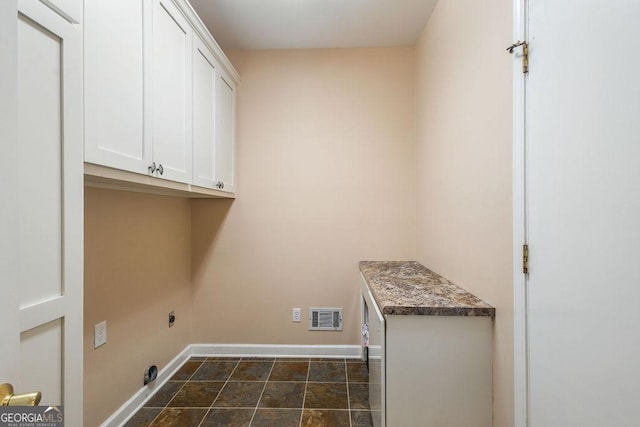 washroom with visible vents, stone finish flooring, cabinet space, and baseboards