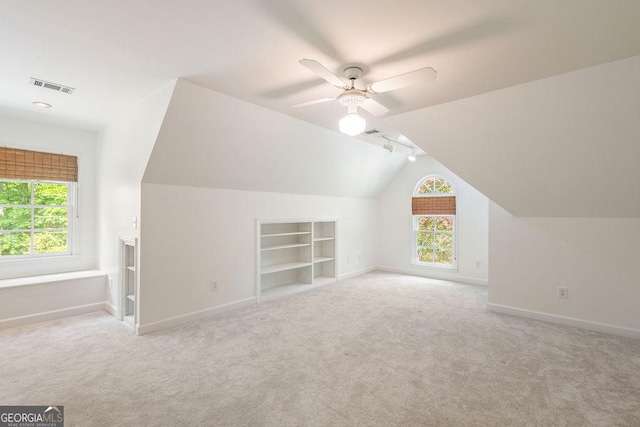 additional living space with baseboards, built in features, lofted ceiling, and plenty of natural light