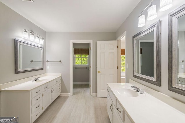 full bath featuring a sink, wood finished floors, and two vanities