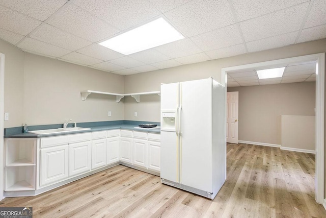kitchen with open shelves, a paneled ceiling, white fridge with ice dispenser, and light wood-style floors