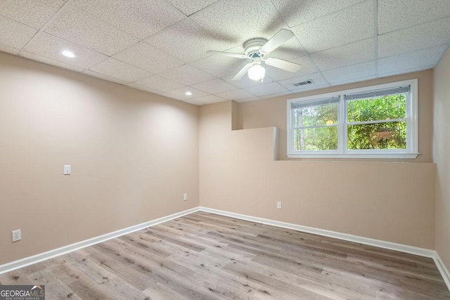 empty room featuring a paneled ceiling, a ceiling fan, visible vents, and wood finished floors