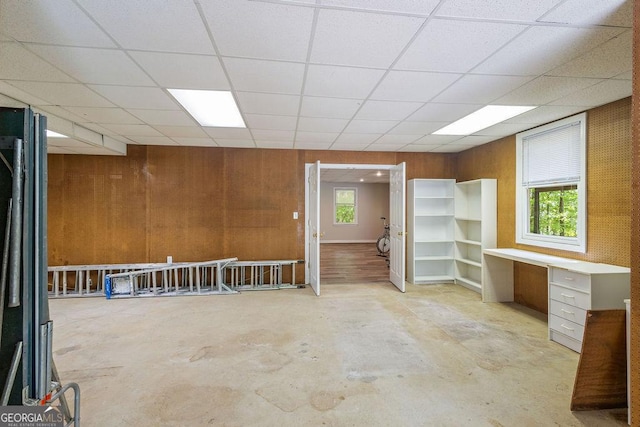spare room with a healthy amount of sunlight, concrete flooring, and a drop ceiling