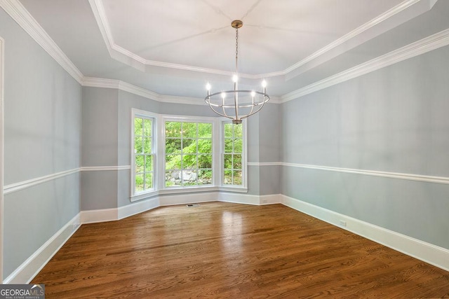 unfurnished dining area with crown molding, a tray ceiling, wood finished floors, and a notable chandelier