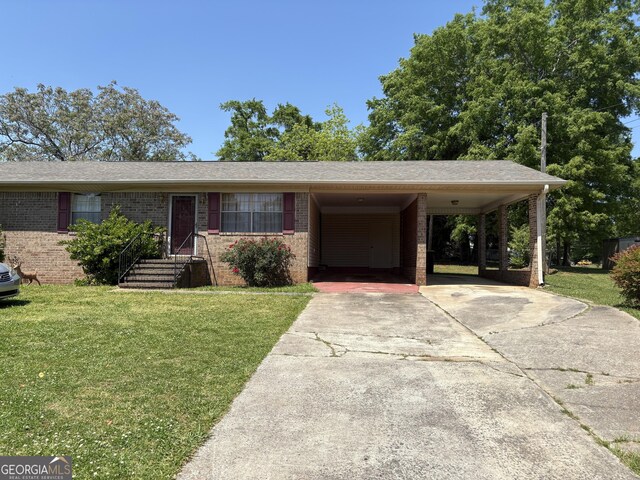 ranch-style home featuring brick siding, a front lawn, driveway, and an attached carport