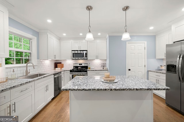 kitchen with stainless steel appliances, a sink, a kitchen island, white cabinets, and tasteful backsplash