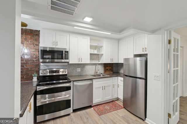 kitchen featuring open shelves, a sink, stainless steel appliances, light wood finished floors, and visible vents