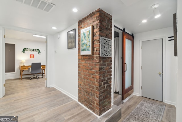 foyer entrance with a barn door, light wood-style floors, baseboards, visible vents, and recessed lighting
