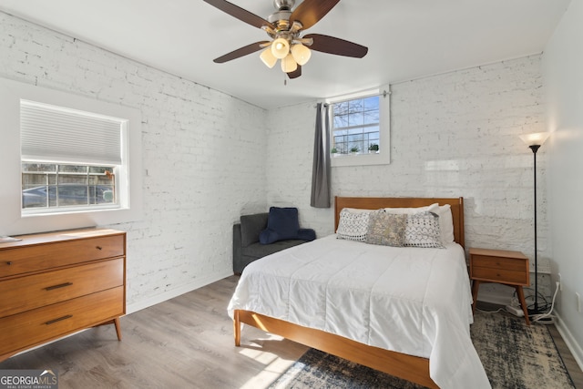 bedroom with brick wall, wood finished floors, and ceiling fan