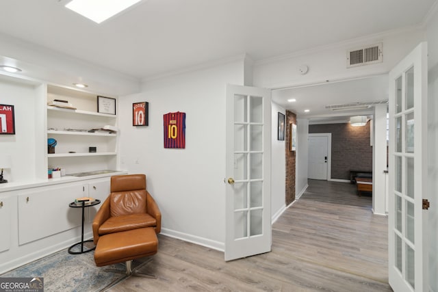 sitting room with crown molding, french doors, light wood finished floors, baseboards, and visible vents