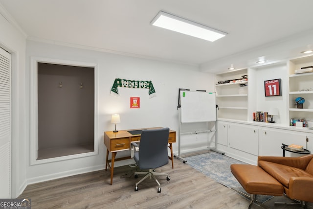 office area featuring light wood-type flooring, baseboards, and crown molding